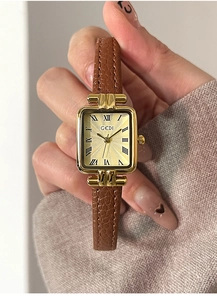 Dettaglio di un orologio vintage quadrato dorato con numeri romani e cinturino in pelle marrone
