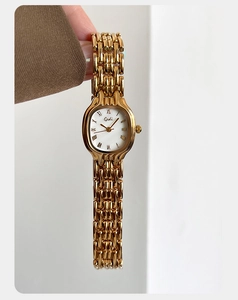Close-up of Gedi luxury women's watch with gold metal link chain and oval Roman dial