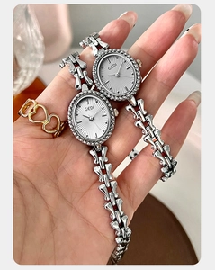 Close-up of elegant silver oval quartz watch with sunray dial and beaded bezel detail