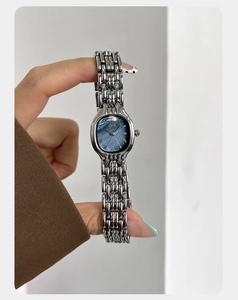 Detailed macro of a silver ladies quartz watch with a textured blue oval dial and roman numerals