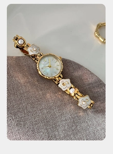 Détail macro de montre GEDI avec chaîne florale blanche, perles et métal doré poli