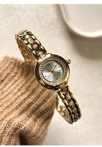 Detail of luxury gold watch with crystal bezel and vintage carved bracelet on knitwear