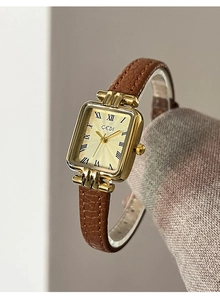 Dettaglio di un orologio vintage rettangolare dorato con numeri romani e cinturino in pelle