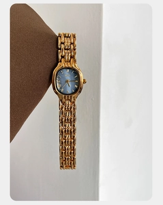 Detail of vintage gold mesh strap watch with light blue mother-of-pearl dial and Roman numerals