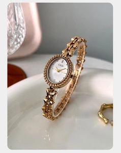 Detailed view of women's vintage gold chain watch with an oval dial on a white plate