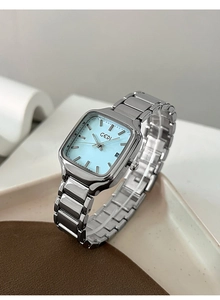 Détail d'une montre carrée argentée avec cadran bleu clair et guichet de date