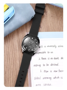 Close-up of minimalist black quartz watch with silicone strap on a wooden desk setup