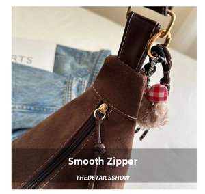 Detail of vintage brown suede tote with smooth gold zipper and stylish pompom charm