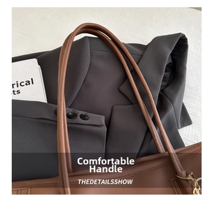 Detail of slim brown leather straps and gold metal hardware on minimalist tote bag