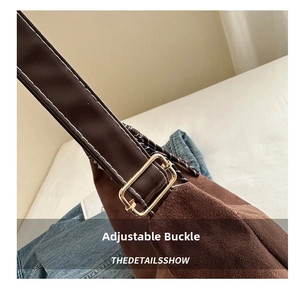 Detailed macro view of brown suede bag showing the adjustable gold metal strap buckle