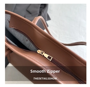 Close-up of golden metal zipper on a premium brown faux leather tote bag with soft lining