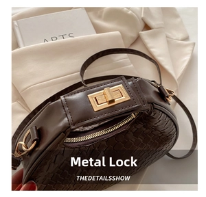 Detail of dark brown woven crescent bag with premium gold hardware lock on beige fabric