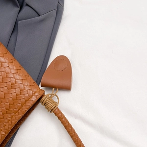 Brown leather woven tote bag with handle details and rustic knotted strap accents