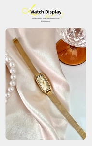 Detail van elegant champagne goud vierkant kwartshorloge op zijde met parel accent
