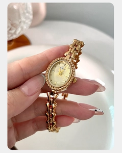 Detail of elegant gold vintage watch with oval sunray dial and heart chain strap