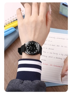 Minimalist black quartz watch with silicone strap shown on wrist in a daily writing scene