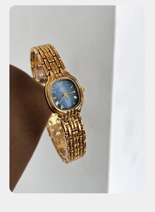 Detail of luxury gold mesh watch band and elegant blue dial with Roman numerals