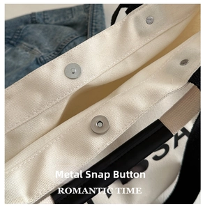 Close-up of magnetic silver metal clasp and durable canvas fabric on a tote bag
