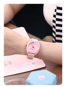 Close-up of a pink square quartz watch with a textured silicone strap on a wooden desk