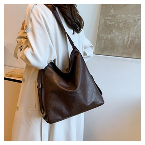 Detail view of large dark brown tote bag with vintage leather texture and strap
