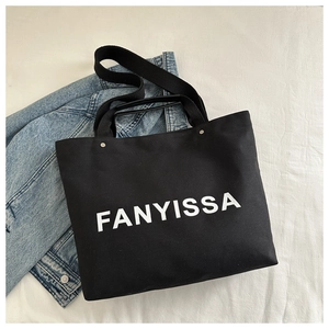 Detail of black canvas tote bag with FANYISSA lettering and metal ring handles