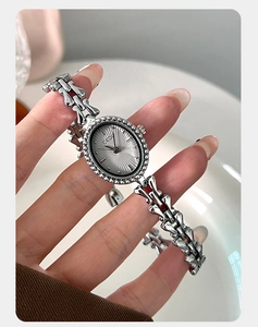 Close-up of vintage silver oval watch dial with sunray pattern and unique metal link strap