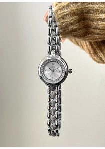 Close-up of silver chain watch with crystal bezel and textured metal bracelet links