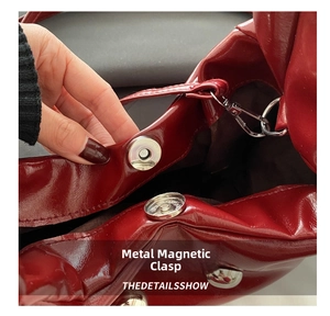 Detail showing the magnetic buckle closure and durable brown lining of the red leather bag