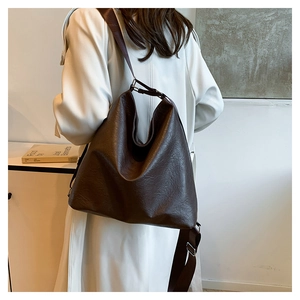 Deep brown large leather tote bag with natural texture shown on a white coat model