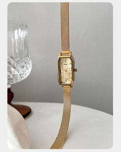 Detailopname van gouden tonneau kwartshorloge met mesh band op een minimalistische achtergrond