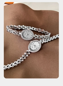 Detail view of oval GEDI chain watches with diamond-set bezels on textured fabric