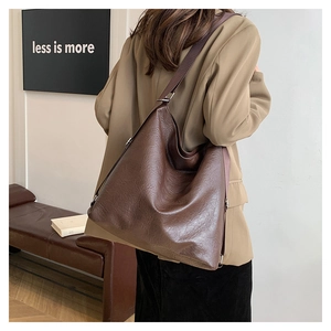 Grand sac cabas en cuir marron porté par un mannequin au décor esthétique minimaliste