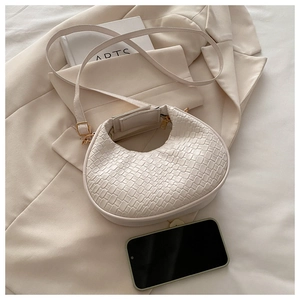Détail du sac demi-lune tressé blanc cassé avec fermeture éclair et bandoulière