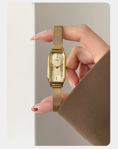 Detail van gouden achthoekig horloge met champagne wijzerplaat en mesh horlogeband