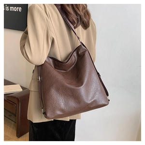 Detail of soft brown leather tote showing pleated texture and wide shoulder strap