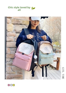 Detail of color-block nylon backpack featuring front zip pocket and plush charm accessory