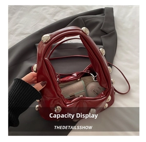 Detail of dark red rivet handbag interior showing storage capacity for wallet and cosmetics