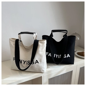 Detail view of large canvas tote bags with letter prints in black and beige colors
