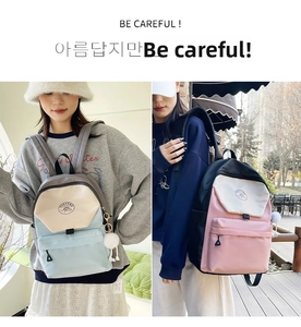 Detail of color-block nylon backpacks in blue and pink with cute pompom charms