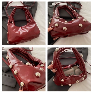 Detail view of burgundy leather bag with silver studs and daily essentials inside