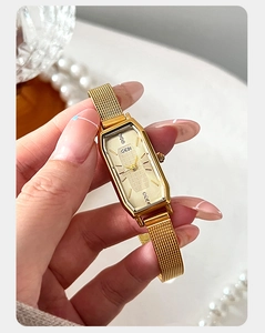 Detail van elegant goudkleurig vierkant horloge met Milanese mesh band en kristallen