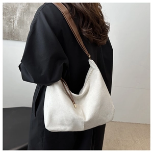 Close-up of beige hobo bag with grainy texture and brown strap shown on a model