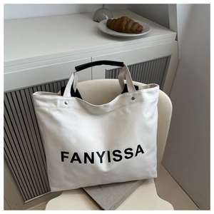 Detail of white canvas tote with black leather handle grip and Fanyissa branding