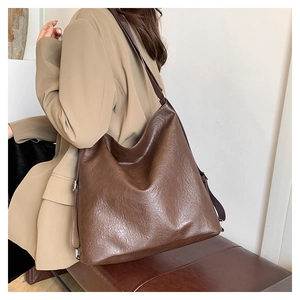 Detail of soft dark brown leather texture and adjustable strap on a large tote bag