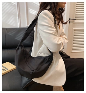 Close-up of black nylon crescent crossbody bag with minimalist zipper and wide shoulder strap