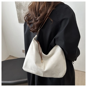 Detail of hobo shoulder bag in cream suede with dark brown strap and zipper tassels