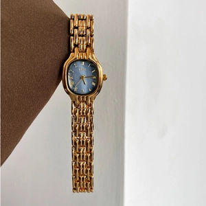 Montre chaîne dorée élégante pour femme avec cadran ovale bleu à chiffres romains