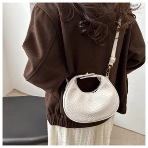 Détail du sac demi-lune blanc crème avec texture gaufrée porté par un mannequin