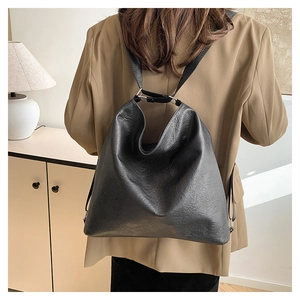 Détail d'un grand sac hobo en cuir souple noir avec bandoulière réglable porté à l'épaule