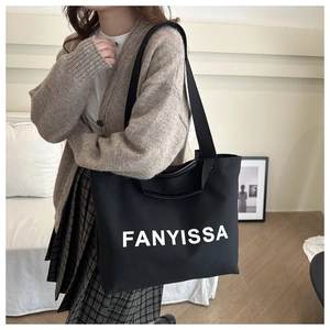 Close-up of black canvas tote bag with white FANYISSA lettering and wide fabric strap